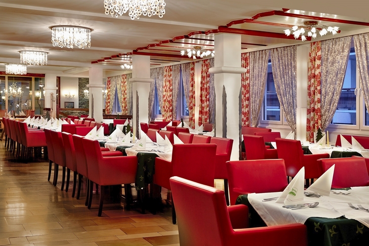 Hotelrestaurant mit roten Stühlen und weiß gedeckten Tischen.