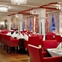 Hotelrestaurant mit roten Stühlen und weiß gedeckten Tischen.
