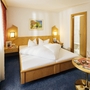 Hell eingerichtetes Hotelzimmer mit Doppelbett, Nachtlampen und Tisch.