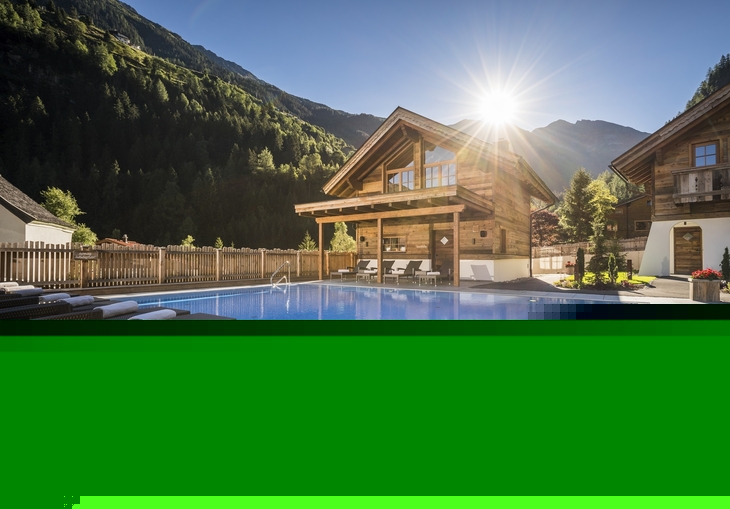Außenansicht eines Wellness-Hüttendorfs mit Pool und Sonnenuntergang in den Bergen.