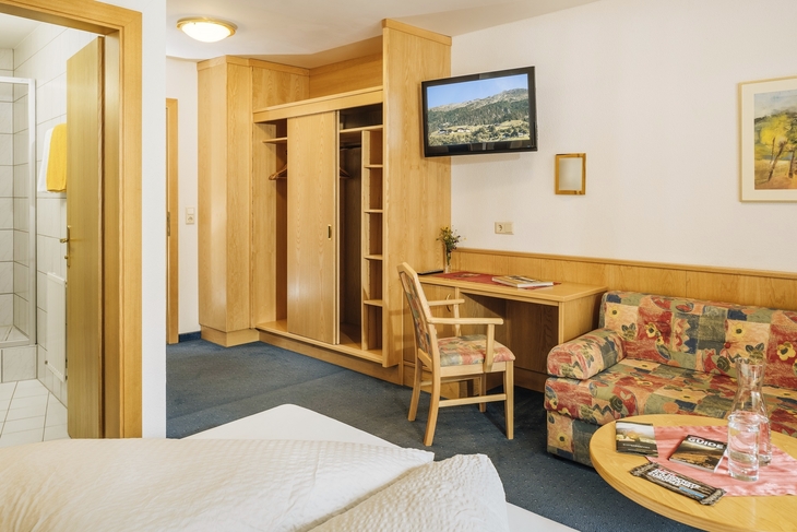 Komfortable Hotelzimmeransicht mit Holzmöbeln und Sofa in warmen Farben.
