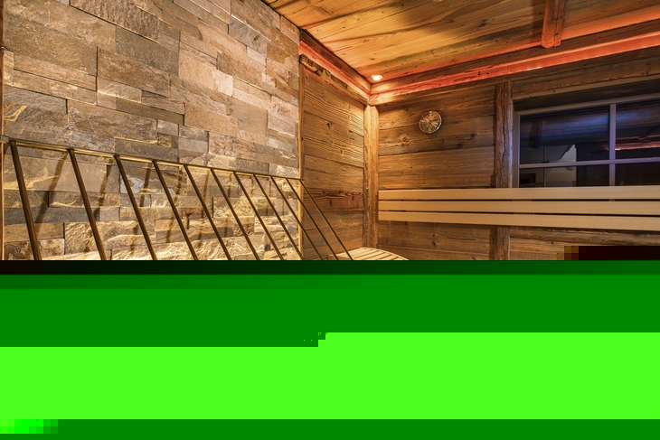 Innenansicht einer gemütlichen Sauna mit Holzbänken und Steinwand.