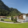 Hotel in Berglandschaft mit grünem Rasen und bewaldeten Hügeln im Sommer.