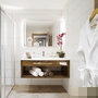 Modernes Hotelbad mit Dusche, Waschbecken, Handtüchern und Bademantel an der Wand.