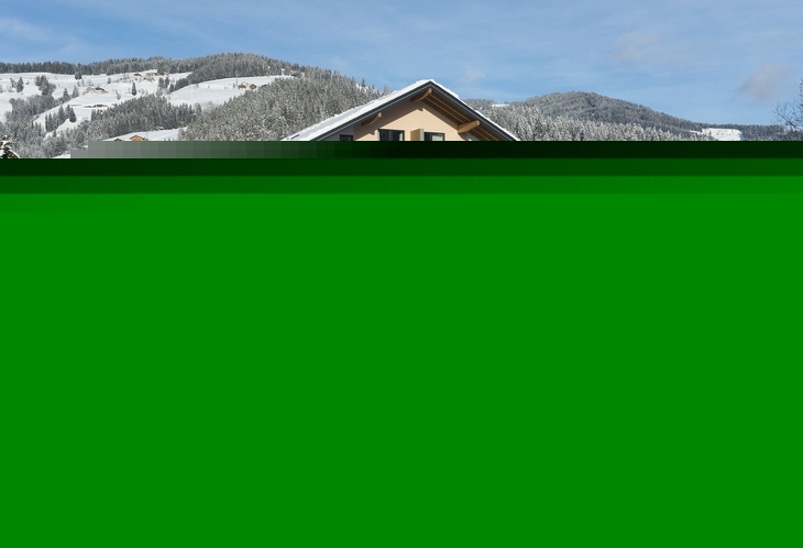 Winterliche Ansicht eines Hotels in Wagrain, umgeben von verschneiten Bergen.