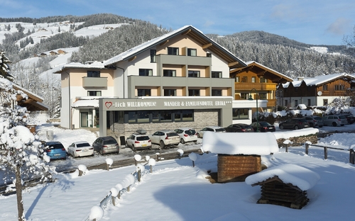 Winterliche Ansicht eines Hotels in Wagrain, umgeben von verschneiten Bergen.