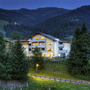 Hotel in Wagrain bei Dämmerung mit Bergen im Hintergrund.