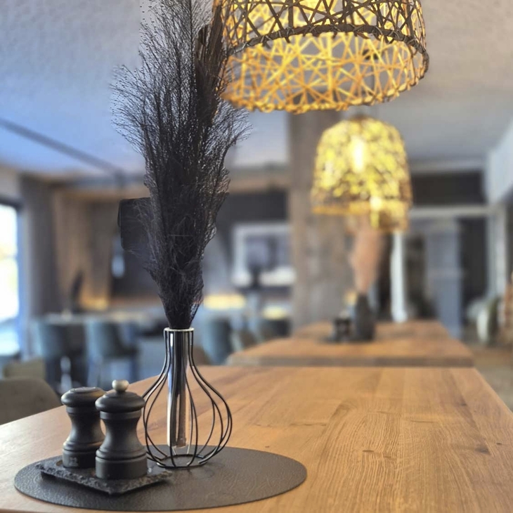 Holztisch im Restaurant mit Dekoration, Gewürzmühlen und Hängelampen.