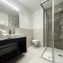 Modernes Hotelbadezimmer mit Dusche, Waschbecken und Toilette.