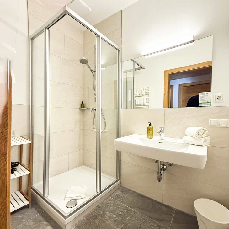 Modernes Badezimmer mit Dusche, Waschbecken und großen Spiegel in einem Hotelzimmer.