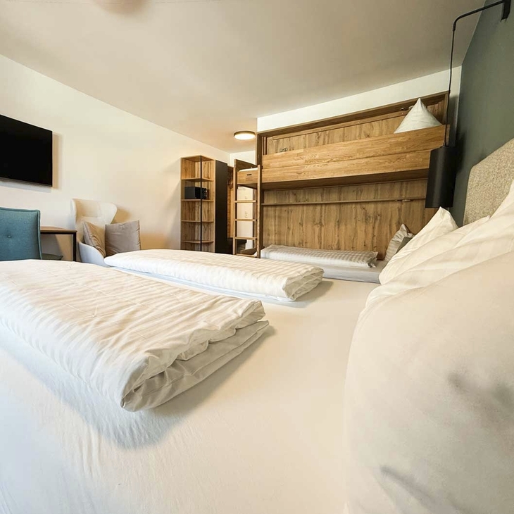 Modernes Hotelzimmer mit Doppelbett und Holzmöbeln im Hotel Erika in Wagrain.