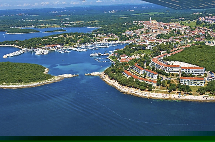 Luftaufnahme eines Küstenresorts bei klarem blauen Wasser und grüner Umgebung.