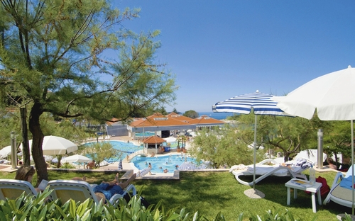 Blick auf Poolbereich des Resorts Belvedere mit Sonnenschirmen und Liegen im Vordergrund.