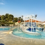 Poollandschaft mit Wasserrutsche im Resort Belvedere, umgeben von Liegestühlen.