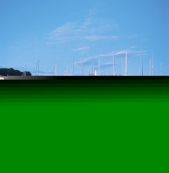 Ein Hafen mit Segelbooten bei Abenddämmerung, ruhiges Wasser, blauer Himmel im Hintergrund.
