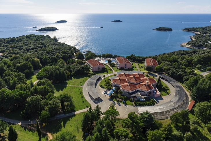 Luftaufnahme eines Resorts am Meer mit kleinen Inseln im Hintergrund.