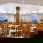 Geräumiges Hotelrestaurant mit Holzstühlen und großen Fenstern, Blick auf das Meer.
