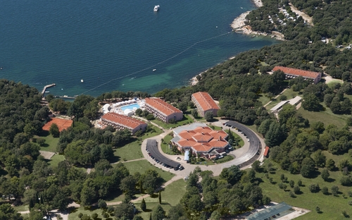 Luftaufnahme eines Resorts mit Gebäuden, Pool und Küste am Meer.