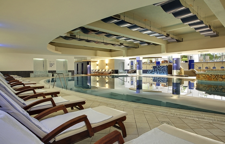 Hotel-Innenpool mit Liegestühlen und moderner Einrichtung.