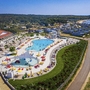 Luftaufnahme eines großen Pools mit Liegestühlen und angrenzendem Strand.