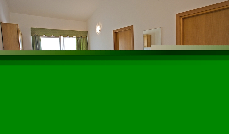Wohnraum mit Sofa, Esstisch, Fernseher und Balkon im Hintergrund.
