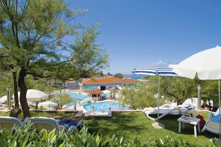 Blick auf Poolbereich des Resorts Belvedere mit Sonnenschirmen und Liegen im Vordergrund.