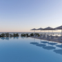 Infinity-Pool mit Liegestühlen und Sonnenschirmen, Meerblick im Hintergrund.