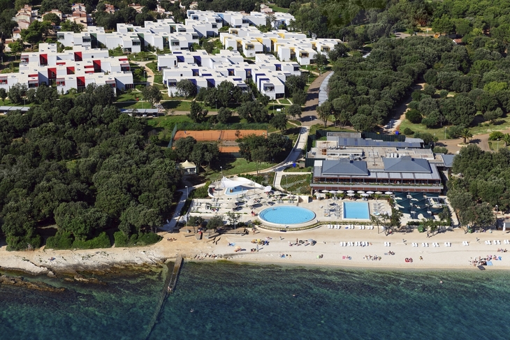 Luftaufnahme eines Resorts mit Pool, Strand und umgebenden Wäldern.
