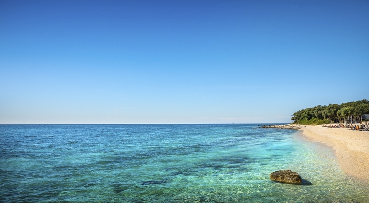 Sandstrand mit klarem, blauem Meer bei Resort Amarin in Rovinj.