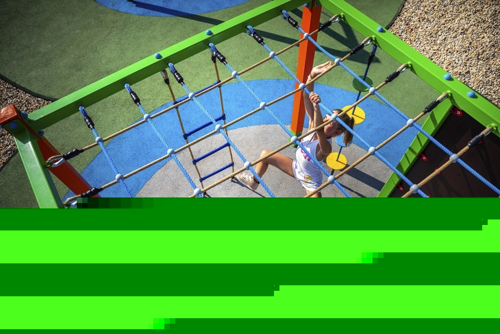 Zwei Kinder spielen auf einem Klettergerüst im Freien.