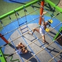 Zwei Kinder spielen auf einem Klettergerüst im Freien.