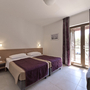 Helles Hotelzimmer mit zwei Einzelbetten, Nachttisch und Balkonzugang.