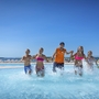 Menschen springen in einen Pool im Resort vor blauem Himmel.