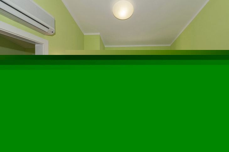 Wohnraum mit Sofa, TV, Schreibtisch und Balkonblick in einer Ferienwohnung.