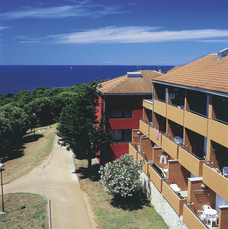 Apartmentgebäude mit Meerblick unter blauem Himmel.