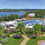 Ferienresort mit Pool, Palmen und Meerblick im Hintergrund.