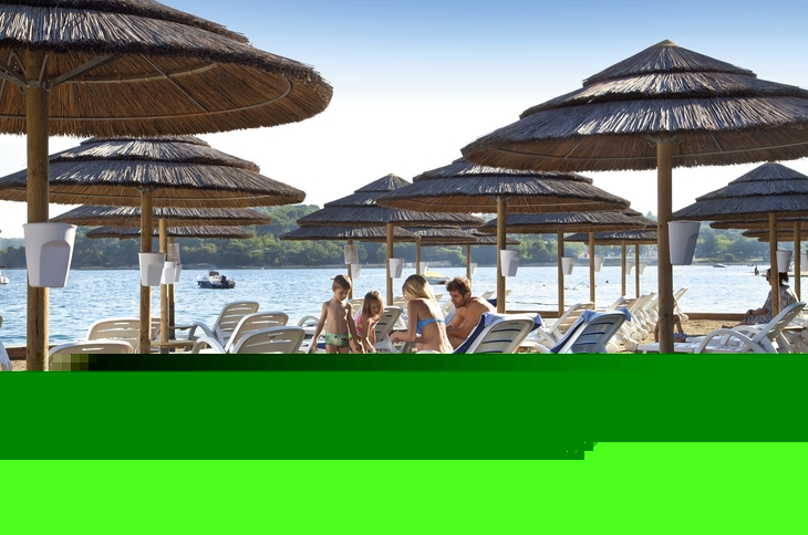 Strand mit Liegestühlen und Strohdächern am Meer im Valamar Tamaris Resort.