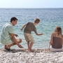 Familie am Kieselstrand mit Blick aufs Meer.