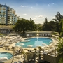 Hotelaußenbereich mit Pool und Sonnenschirmen, grünes Umfeld.
