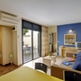 Wohnzimmer eines Ferienapartments mit Sofa, Tisch, Fernseher und Zugang zur Terrasse.