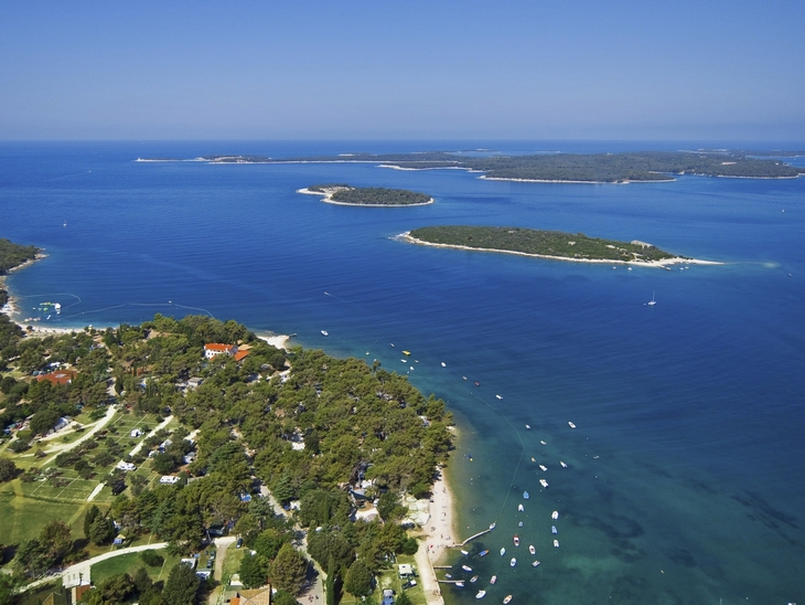 Luftaufnahme eines Campingplatzes am Meer mit klarem Wasser und kleinen Inseln.