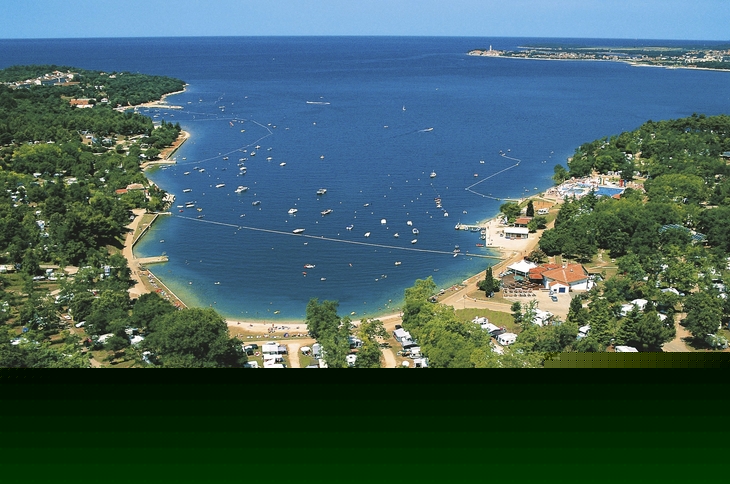 Luftansicht eines Campingplatzes am Meer mit Sandstränden und vielen Bäumen.