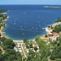Luftansicht eines Campingplatzes am Meer mit Sandstränden und vielen Bäumen.
