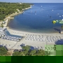 Luftaufnahme eines Strandes mit Liegestühlen und einem Wasserpark auf dem Meer.