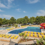 Poolanlage mit Liegestühlen und Wasserrutschen in einem Camping-Resort.