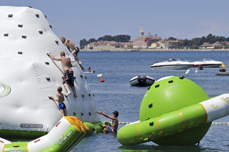 Kinder klettern auf einem Wasserpark-Spielzeug im Meer nahe eines Resorts.