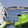 Kinder klettern auf einem Wasserpark-Spielzeug im Meer nahe eines Resorts.