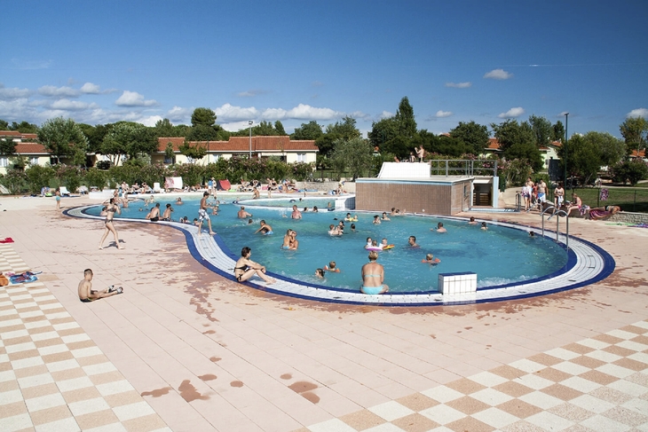 Menschen schwimmen und entspannen in einem Außenpool bei sonnigem Wetter.