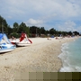 Strand mit Tretbooten und Badegästen am Meer an einem sonnigen Tag.