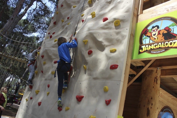 Kind klettert an einer Kletterwand im Abenteuerpark.